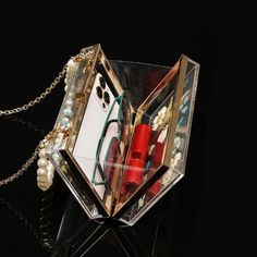 an origami box with jewelry inside on a black surface and a chain attached to it