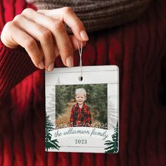 a person holding a christmas ornament in their left hand and wearing a red sweater