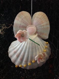 a sea shell ornament with flowers hanging from it