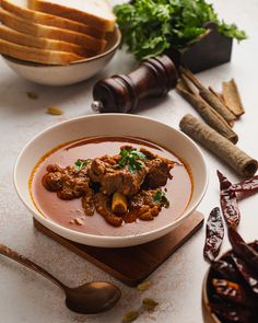 a white bowl filled with soup next to bread and other food on a wooden cutting board