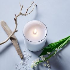 a white candle sitting on top of a table next to flowers and a wooden cross