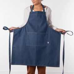 a woman in an apron holds on to a pair of blue denim bib's