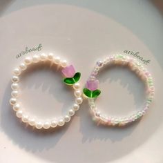 two bracelets with flowers on them sitting on a white plate next to each other