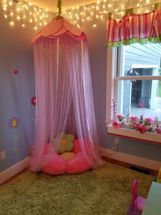 a pink canopy bed in a child's bedroom with fairy lights on the ceiling