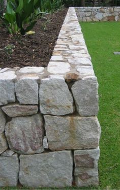 a stone wall in the middle of a grassy area