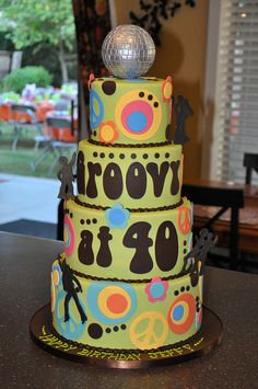 a three tiered cake with an disco ball on top is decorated in bright colors