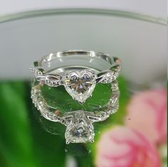 an engagement ring is sitting on top of a glass surface with flowers in the background