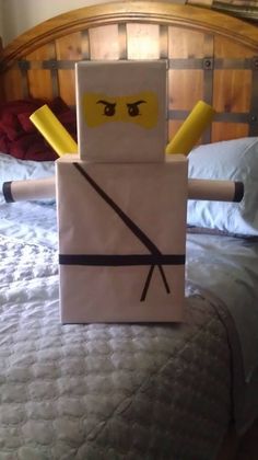 a bed with a paper bag made to look like a lego figure on top of it