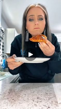 a woman holding a plate with a slice of pizza on it in front of her face