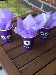 three cups with purple tissue paper in the shape of skulls and eyes are sitting on a wooden table