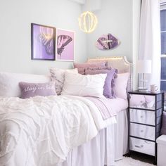 a bed with white sheets and purple pillows