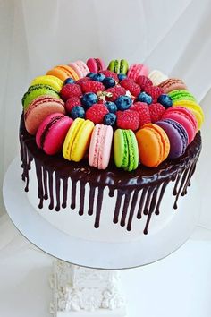 a white cake topped with lots of colorful macaroons