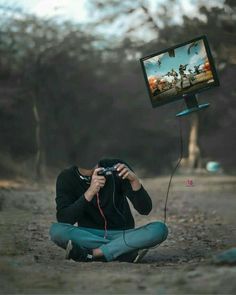 a man sitting on the ground holding a camera and looking at a television screen in front of him