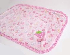 a pink baby blanket with a strawberry on the bottom and polka dots around the edges