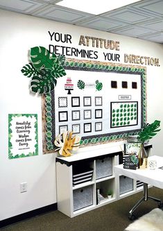 an office cubicle with a white board and green plants