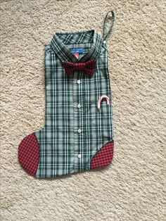 a green plaid shirt with a red bow tie is laying on the floor next to a pair of scissors