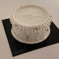 a white cake sitting on top of a black plate