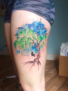 a woman's thigh with a tree and birds painted on the side by watercolors