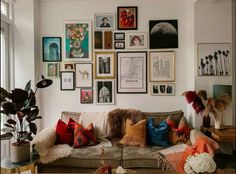 a living room filled with lots of pictures on the wall and couches covered in pillows