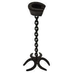 a black metal object with chains hanging from it's center and two claws on the bottom