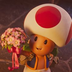 a figurine holding a bouquet of flowers in it's hand and wearing a mushroom hat