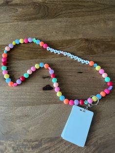 a necklace with a tag attached to it on a wooden table next to a string of beads