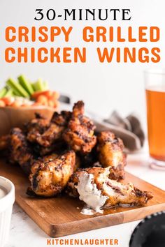 crispy grilled chicken wings on a cutting board next to a glass of beer