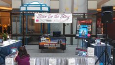 there is a woman standing in front of a table with speakers and signs on it