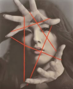 a woman holding her hands over her face with red lines in the shape of a star