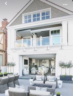 an outdoor living room and patio area with furniture in front of a large white house