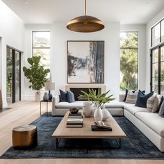 a living room with white couches and blue rugs in front of large windows