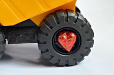 a yellow toy truck with a heart on it's front wheel and tire rim