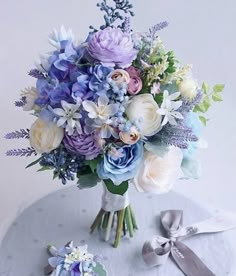 a bouquet of flowers sitting on top of a white table next to a silver ribbon