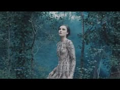 a woman is standing in the woods wearing a snake skin dress and holding her hand on her hip