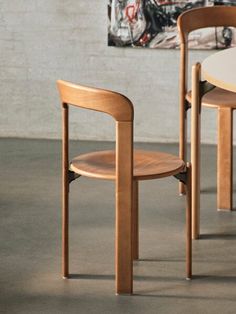 two wooden chairs sitting next to each other in front of a painting on the wall