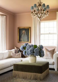 a living room filled with furniture and a chandelier hanging from the ceiling next to a window