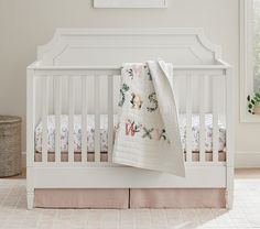 a white crib with a blanket on top of it