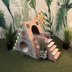 there is a cat house made out of cardboard and some plants in front of it