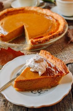 a slice of pumpkin pie on a plate with a fork in front of the pie