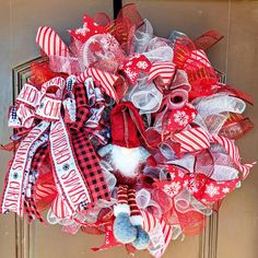 a red and white christmas wreath on the front door with snowflakes, plaid ribbon and teddy bears