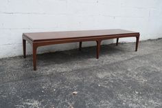 a wooden table sitting on top of a cement floor next to a white brick wall