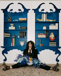 a woman is sitting on the bed with flowers