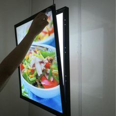 a person is pointing at a video screen with food on it