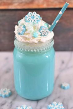 a blue mason jar filled with frosting and snowflakes on top of a table