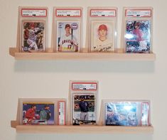 some baseball cards are hanging on the wall in front of two wooden shelves with pictures