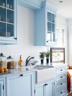 a kitchen with blue cabinets and white counter tops is pictured in this image, there are two vases on the window sill