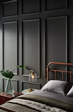 a bedroom with black walls and a metal bed frame, along with a green plant in a glass vase