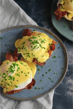 two plates filled with eggs and bacon on top of a blue plate next to a white napkin