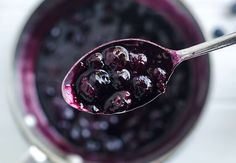 a spoon full of blueberries sitting in a bowl