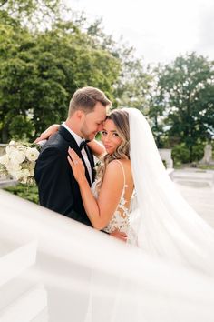 a bride and groom embracing each other in front of the white staircase at their wedding